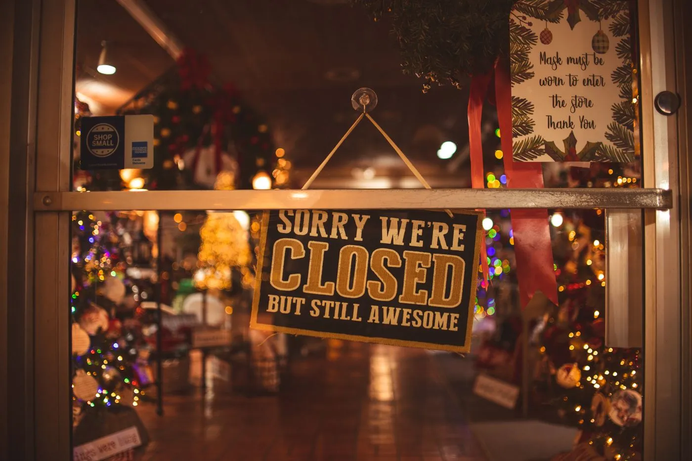 A 'Sorry we're closed' sign on a shop door decorated for Christmas