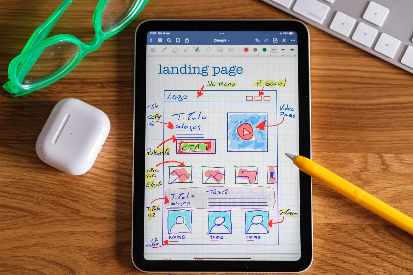 A hand-drawn landing page wireframe on a tablet beside a keyboard