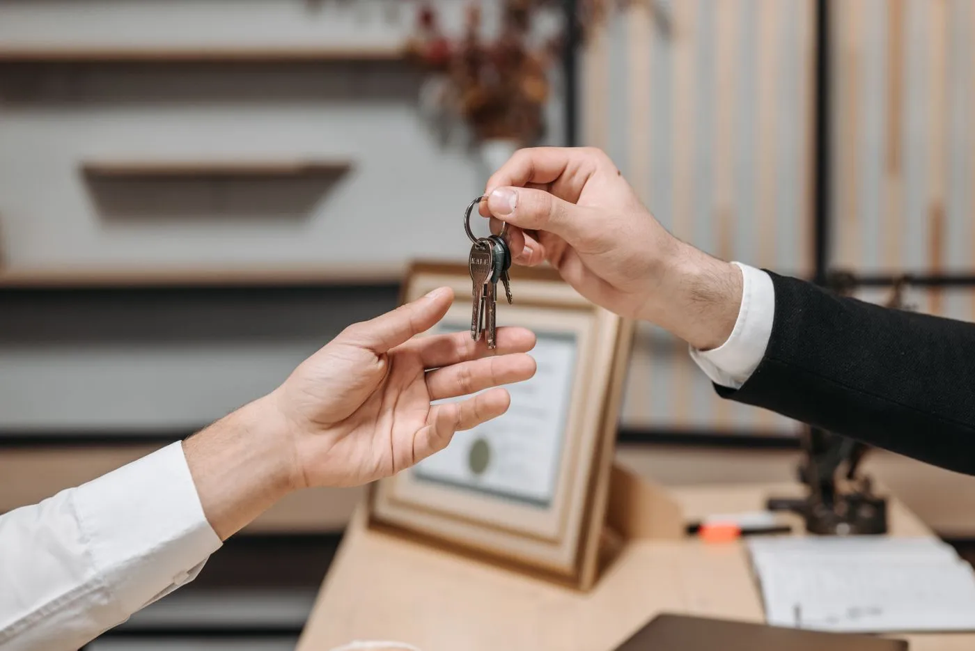 Two people exchanging a set of keys across an office desk