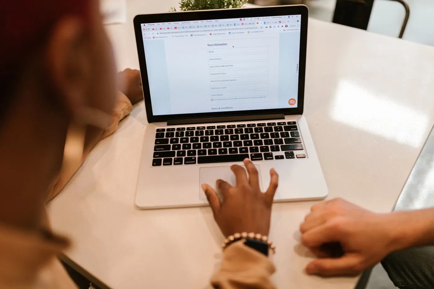 Two people at a laptop filling out a long online form